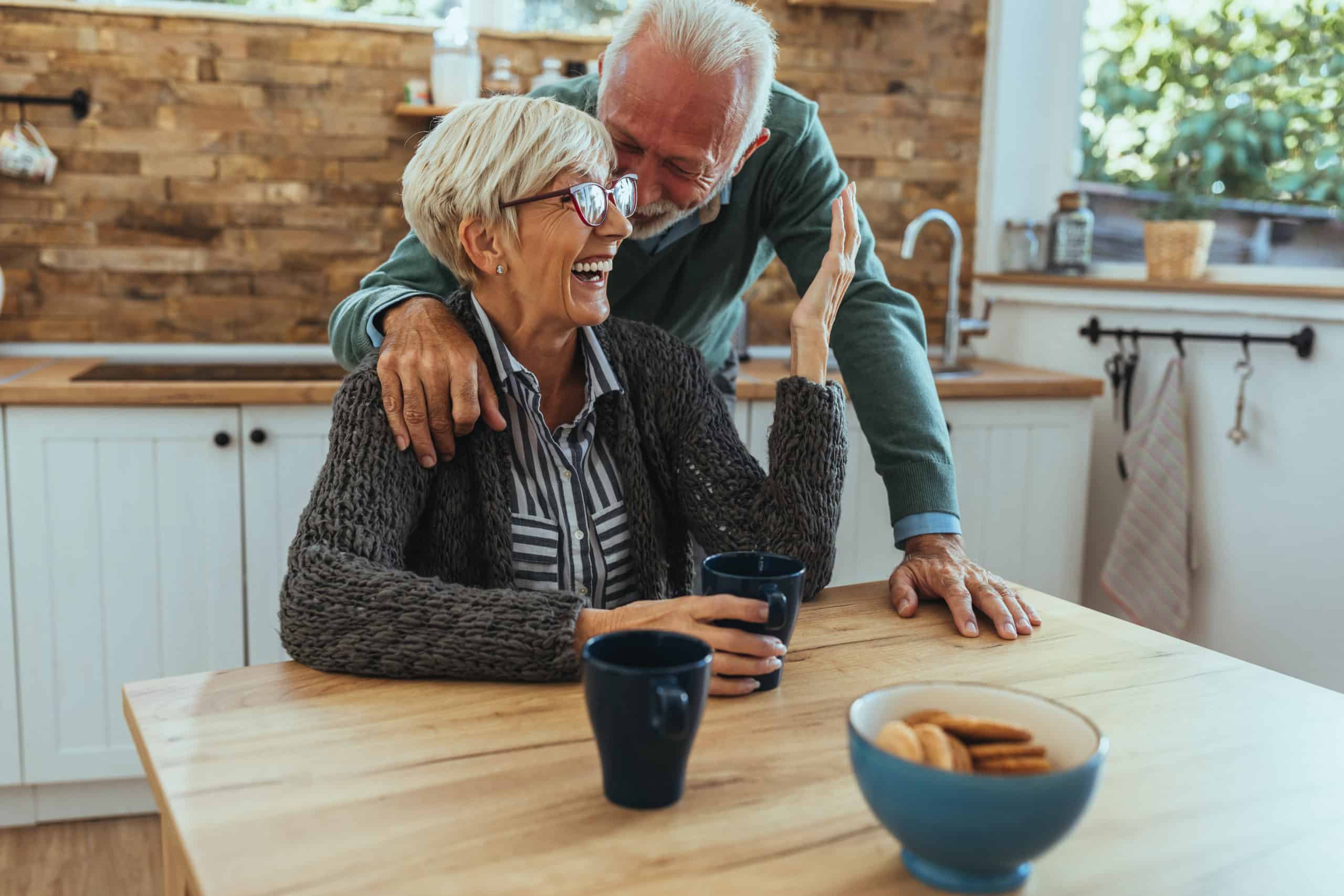 Older couple embracing in their kitchen.