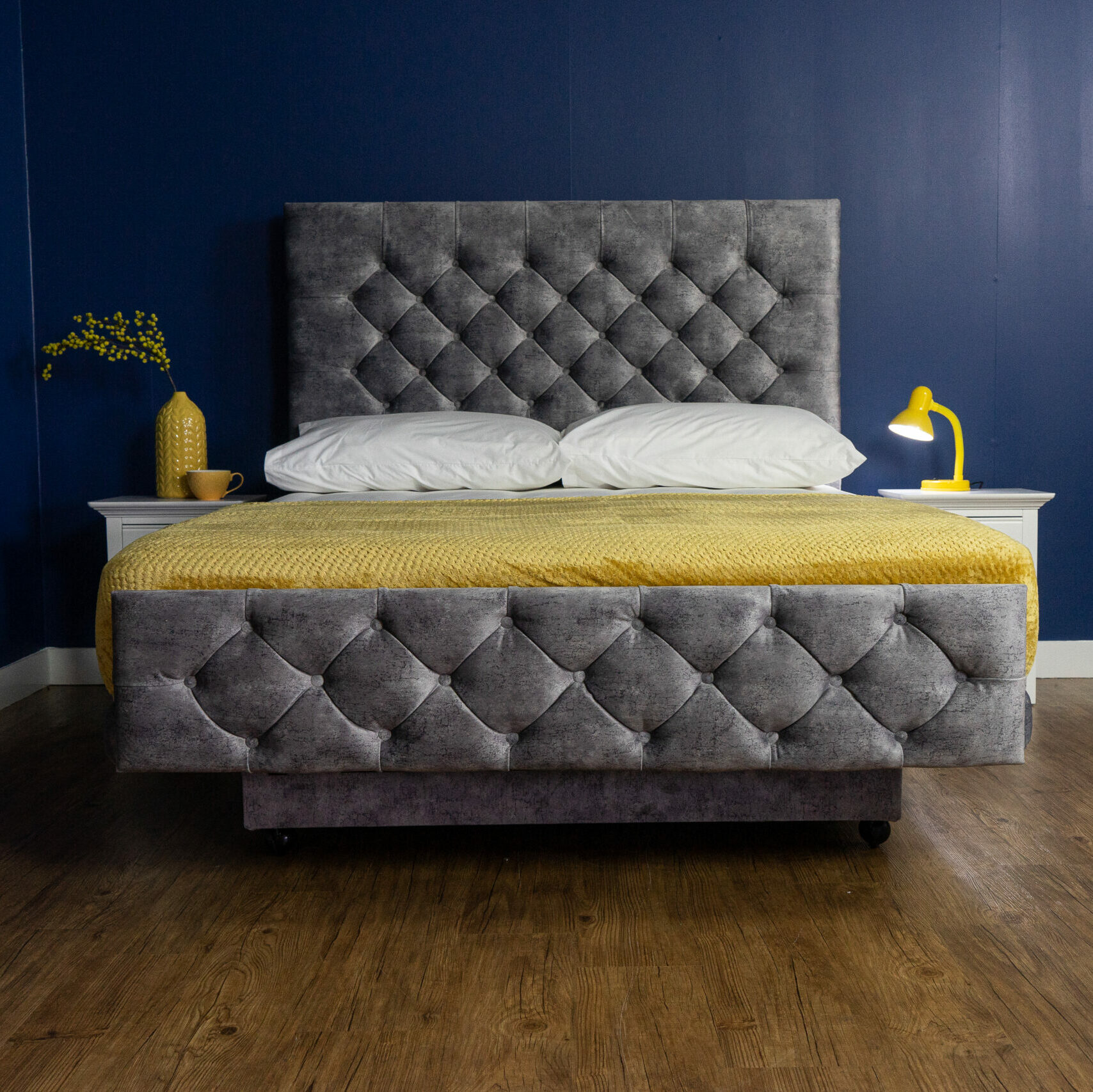 The Heritage Chatsworth Adjustable Bed in grey fabric with buttoned a headboard. A yellow blanket has been place on top of the duvet.