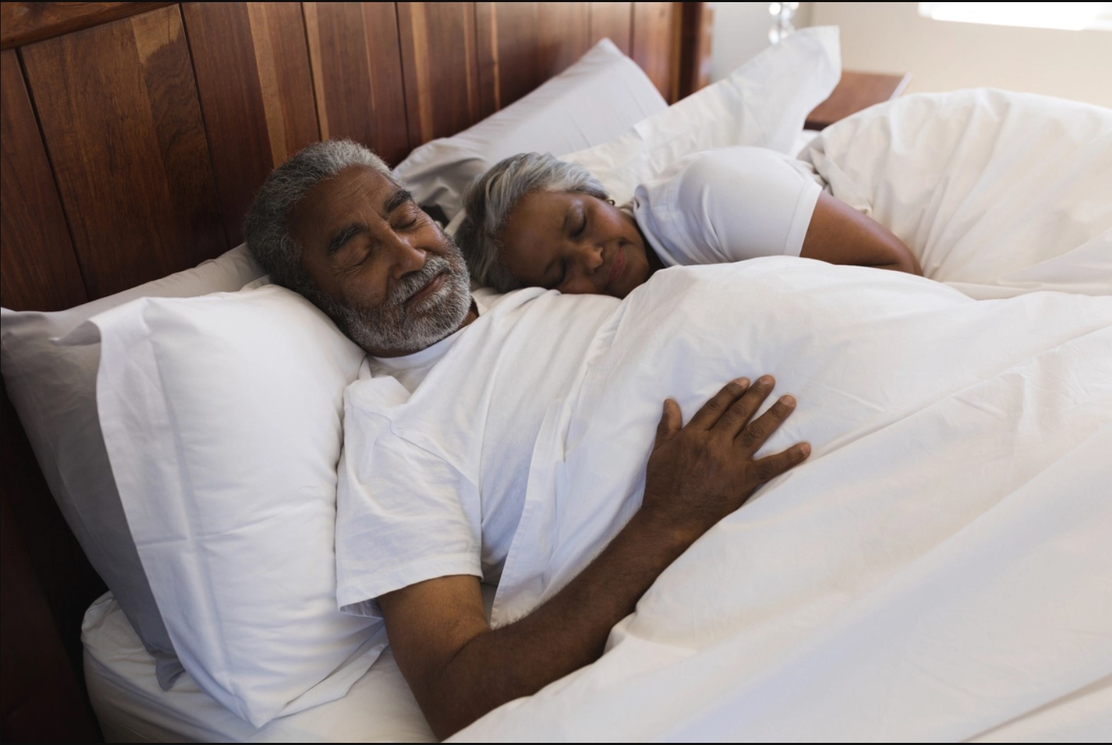 A couple sleeping comfortably in bed.